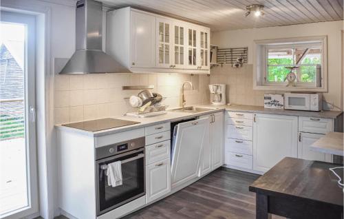 uma cozinha com armários brancos e um forno com placa de fogão em Awesome Home In Lckeby With Kitchen 