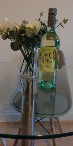 a bottle of wine sitting next to a vase with flowers at Bright, Nice Interior, Close to the City, 2 Bedroom Apartment in London