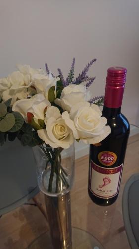 a vase with white flowers next to a bottle of wine at Bright, Nice Interior, Close to the City, 2 Bedroom Apartment in London