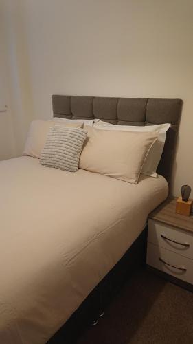 a bed with white sheets and pillows on it at Bright, Spacious, Nice Interior, Close to the City, 2 Bedroom Apartment in London