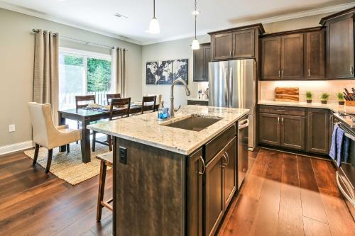 a kitchen with wooden cabinets and a dining room with a table at Downtown Townhome Walk to Dine and Shop on Broad St in Southern Pines