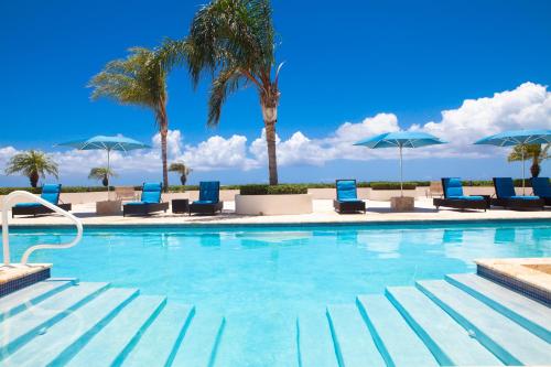 a swimming pool with blue chairs and palm trees at New Listing La Vista Azul Spacious 1 Bedroom Condo in Turtle Cove