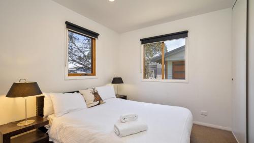 a bedroom with a white bed and two windows at Mitchell in Dinner Plain