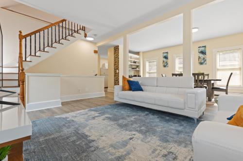 a living room with a white couch and a staircase at Skyrise Two Stories - Centrally Located in Brookline