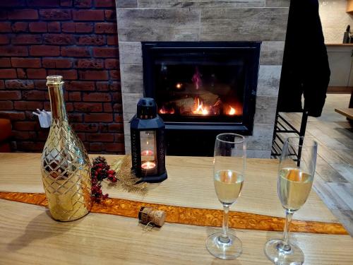 two glasses of wine on a table with a fireplace at Urocza Kryjówka ze SPA in Lesko