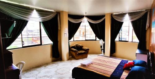 1 dormitorio con 1 cama, 1 silla y ventanas en Hostal Carolina, en Yantzaza
