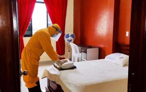 una persona en una habitación de hotel preparando una cama en Hostal Carolina, en Yantzaza