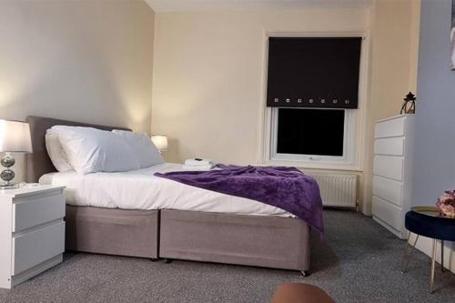 a bedroom with a bed with a purple blanket and a window at Cosy 3BR Hastings House in Maidstone Kent in Kent