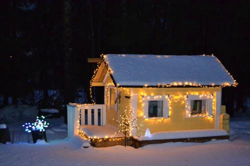 a small house covered in christmas lights in the snow at Guesthouse Torppa in Korkeakoski