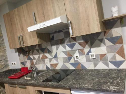 a kitchen with a sink and a tiled wall at Serrano T1 centro da cidade in Guarda
