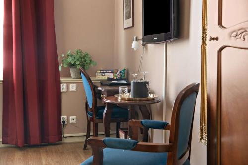 a room with a table with chairs and a television at Best Western Hotel Gamla Teatern in Östersund