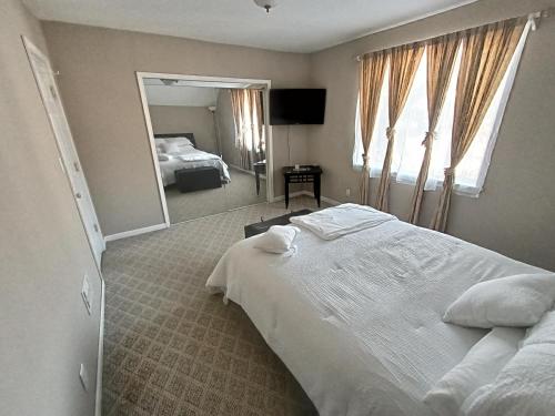 1 dormitorio con 1 cama blanca grande y espejo en Cozy Updated 3-BR apartment near Peace Bridge, en Buffalo