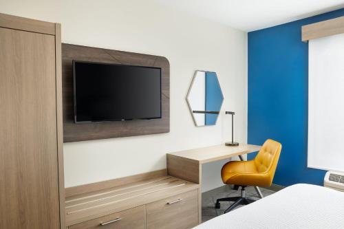 a bedroom with a desk and a tv on a wall at Holiday Inn Express Hotel & Suites Port St. Lucie West by IHG in Port Saint Lucie