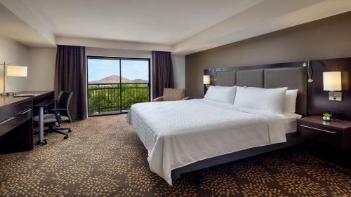 Habitación de hotel con cama, escritorio y ventana en Holiday Inn and Suites Phoenix Airport North, an IHG Hotel en Phoenix