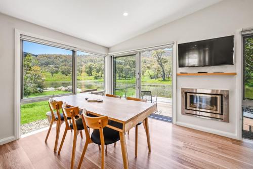 a dining room with a table and chairs and a fireplace at Stillwater Chalet A - Amazing Lakefront 2BR Chalet l BBQ l Gym l Tennis l Indoor Pool in Crackenback