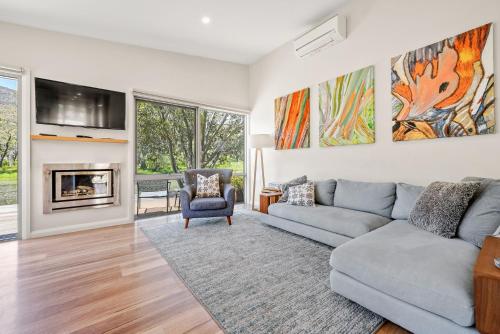 a living room with a couch and a fireplace at Stillwater Chalet A - Amazing Lakefront 2BR Chalet l BBQ l Gym l Tennis l Indoor Pool in Crackenback