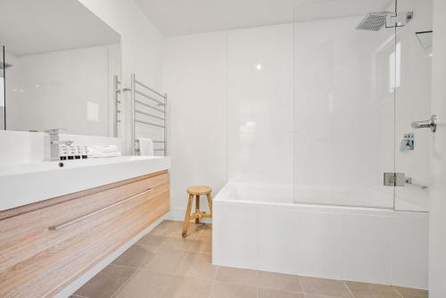 a white bathroom with a tub and a sink at Stillwater Chalet A Crackenback in Crackenback