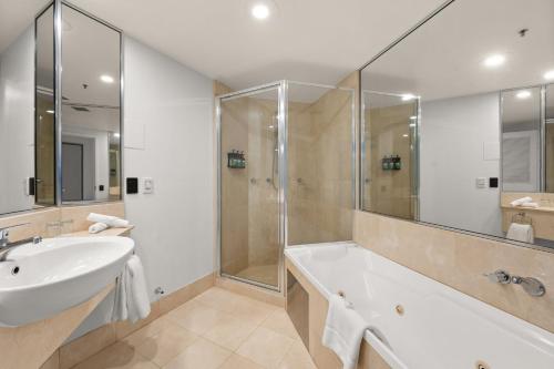 a bathroom with a tub and a sink and a shower at Crowne Plaza Surfers Paradise by IHG in Gold Coast