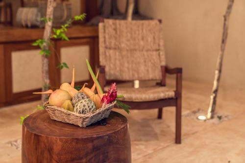 a basket of fruit on a wooden table with a chair at Oriundo Luxury Nature Villas in Valladolid