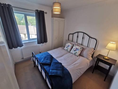 um quarto com uma cama com lençóis azuis e uma janela em Twyngaer, a spacious 3 bedroom bungalow sleeps 6 em Knighton