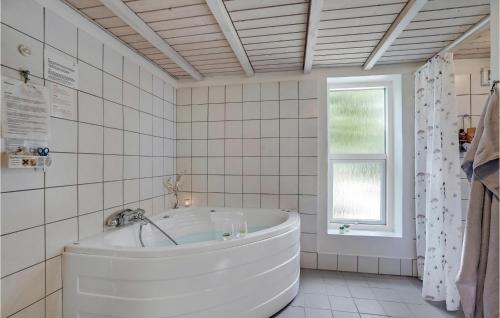 uma banheira branca numa casa de banho com azulejos brancos e uma janela em Lovely Home In Spttrup With Sauna em Spottrup
