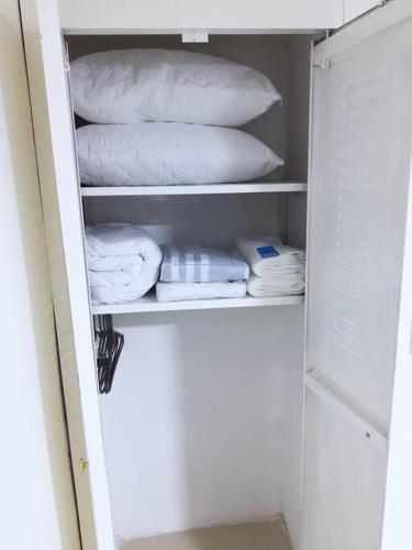 un armario lleno de toallas y almohadas blancas en Apartaestudio con parking privado y accesor a gym con piscina, en Cali