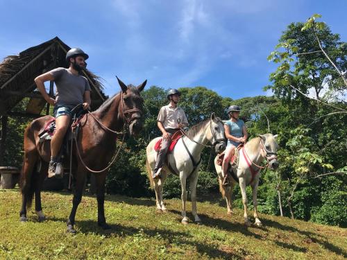 three people are riding horses on a field at Hacienda Mil Bellezas in Quepos