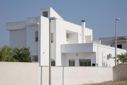 a white building with a fence in front of it at Casa Solento in Maruggio
