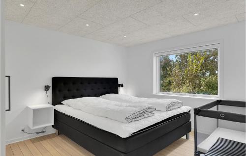 a bedroom with a bed with a black headboard and a window at Amazing Home In Tranekr With Wifi in Tranekær