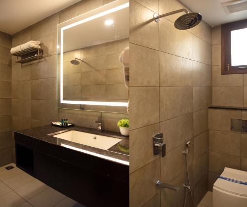 uma casa de banho com um lavatório e um espelho em The Madras Grand em Chennai