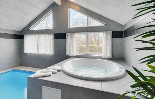 a large bathroom with a tub and a swimming pool at Stunning Home In Væggerløse With Sauna in Marielyst