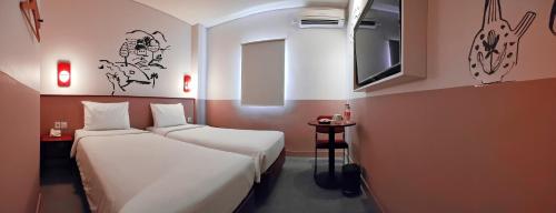 a hotel room with two beds and a tv at Kotta GO Yogyakarta in Yogyakarta