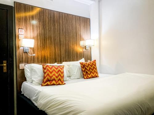 - un lit blanc avec deux oreillers dans une chambre d'hôtel dans l'établissement ALEXANDRIA COURT, à Lekki