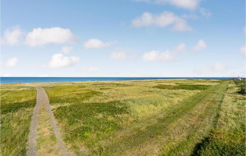 a field with tracks in the grass and the ocean at Lovely Home In Løgstør With Kitchen in Løgstør