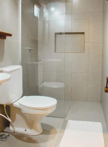 a bathroom with a toilet and a glass shower at Pousada El Capitan in Barra Grande