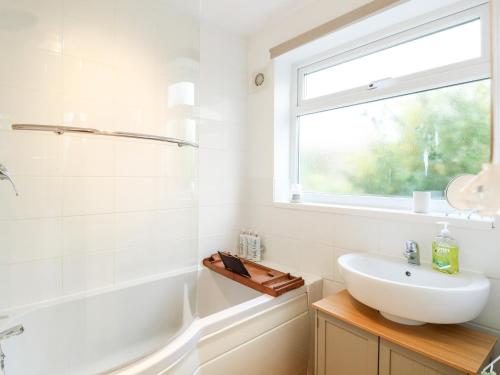 a white bathroom with a sink and a window at Phloxhaven in Norwich