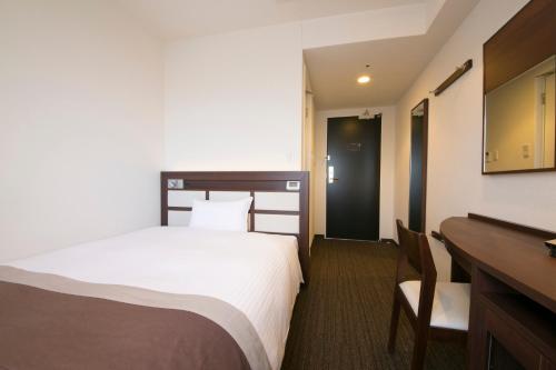 a hotel room with a bed and a desk at Urban Hotel Minami Kusatsu in Kusatsu