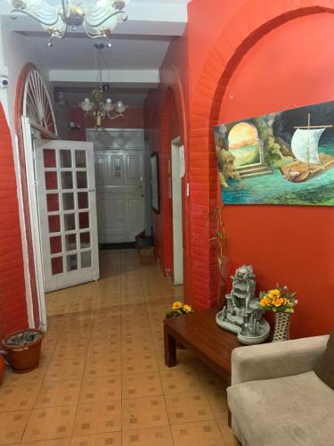 sala de estar con paredes de color naranja, sofá y mesa en Hostal THE IMPERIAL, en Quito