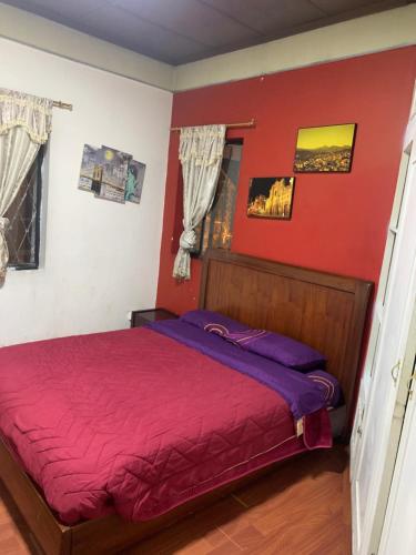 1 dormitorio con 1 cama con pared roja en Hostal THE IMPERIAL, en Quito