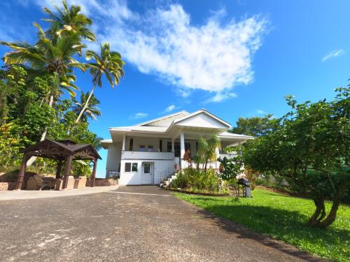 a white house with palm trees and a driveway at Hilo Bay Oceanfront Bed and Breakfast in Hilo