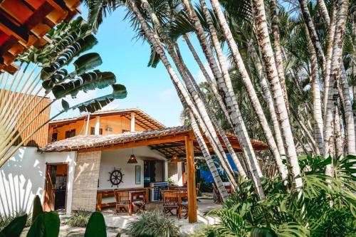 a house with palm trees in front of it at Pousada El Capitan in Barra Grande