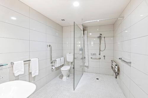 a white bathroom with a shower and a toilet at Alexandra Hills Hotel in Cleveland