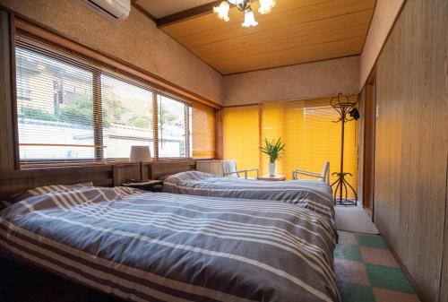 two beds in a room with yellow walls and windows at Villa Higashi Fujita Resort in Moroyose