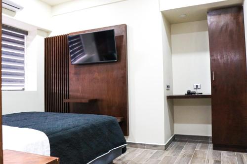 1 dormitorio con 1 cama y TV en la pared en HOTEL MISION 11, en Tijuana