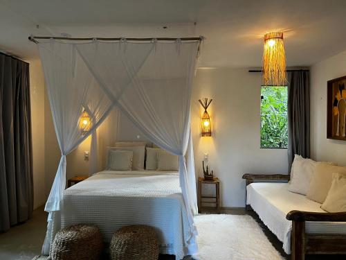 a bedroom with two beds and a canopy bed at Casa Viva Trancoso in Trancoso