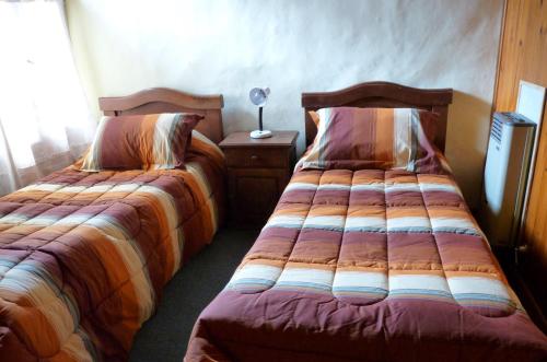 1 dormitorio con 2 camas y mesa con lámpara en San martin de los andes cabaña en San Martín de los Andes