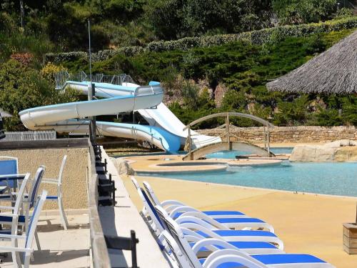 un toboggan au milieu d'une piscine avec des chaises dans l'établissement Duplex T3 6 pers avec terrasse, piscines et parking - Salavas - FR-1-382-32, à Salavas
