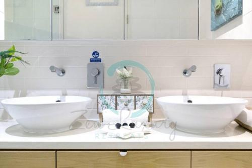 ein Badezimmer mit zwei weißen Waschbecken auf der Theke in der Unterkunft ZEN POINT PENTHOUSE 3-BR Executive W/front Retreat in Darwin
