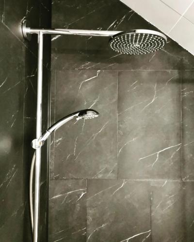 une douche avec pommeau de douche dans une salle de bain dans l'établissement Hydrangea Cottage Arras, à Saint-Laurent-Blangy