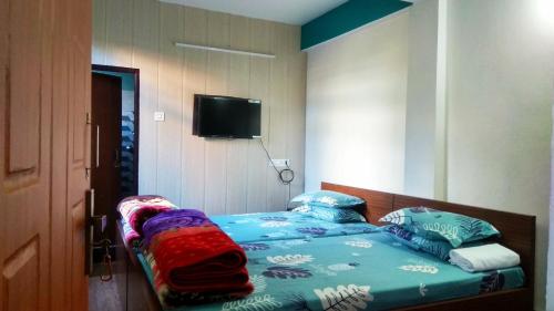 1 dormitorio con 1 cama y TV de pantalla plana en Sunshraya Homestay, en Darjeeling